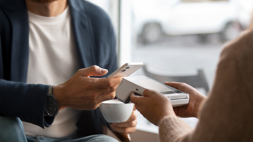 Customer making a contactless payment using a card machine for retail in an Irish shop